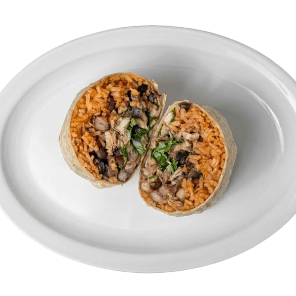 A Tacos El Primo burrito, cut in half, revealing rice, black beans, chicken, and cilantro.