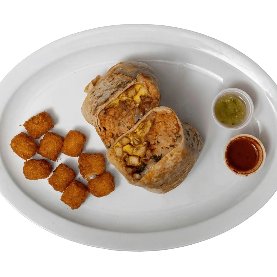 A Tacos El Primo burrito, cut in half, with tater tots and two dipping sauces.
