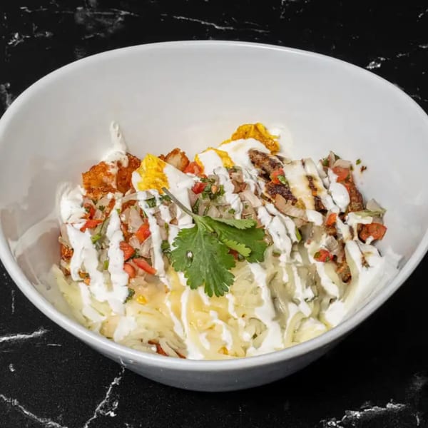A Tacos El Primo Mexican bowl with meat, pico de gallo, cheese, and sour cream.