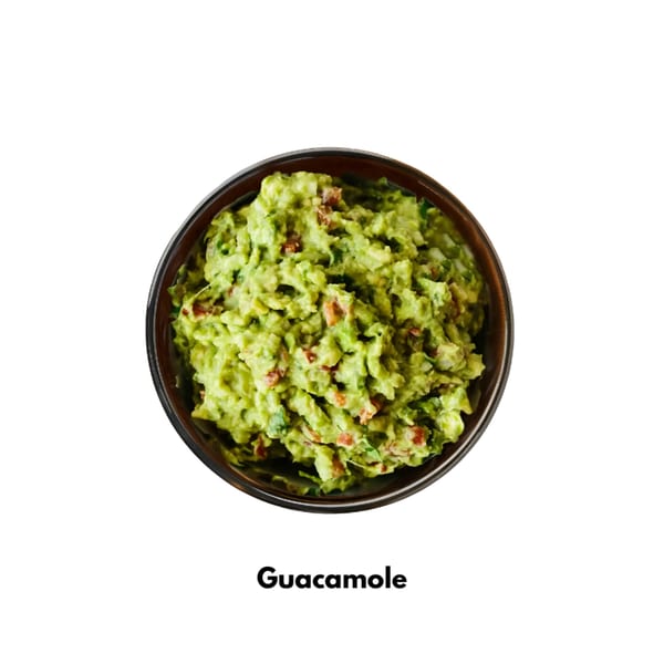 A dark bowl filled with chunky, vibrant green guacamole, garnished with red tomato pieces.