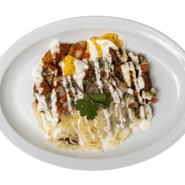 A Mexican dish with fried potatoes, eggs, pico de gallo, and crema on a white oval plate.