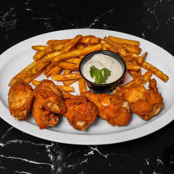 Crispy fried chicken wings and golden french fries with a side of creamy ranch dip.