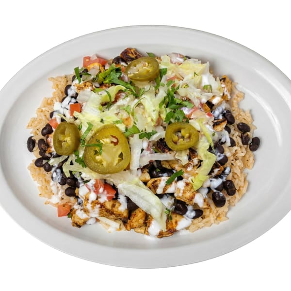 A Tacos El Primo Mexican chicken bowl with rice, black beans, lettuce, tomatoes, and jalapeños.